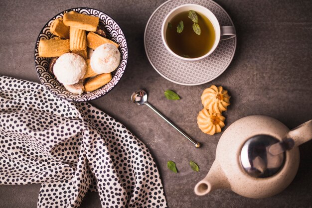 Ciastka i ziołowe herbaty w pobliżu polka przerywana tkanina na chropowatej powierzchni