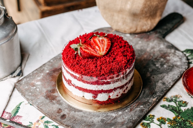Ciasto owocowe z czerwonym widokiem ozdobione okrągłymi truskawkami i kremową, słodką uroczystością urodzinową na brązowym biurku
