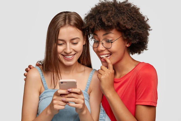 Ciekawa szczęśliwa międzyrasowa nastolatka śmieje się podczas oglądania zabawnego wideo