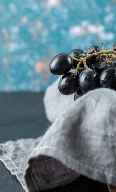 Ciemne świeże winogrona w koszu na kolorowym