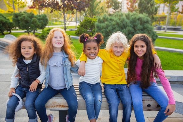 Ciepły. Międzyrasowa grupa dzieci, dziewcząt i chłopców bawiących się razem w parku w letni dzień.