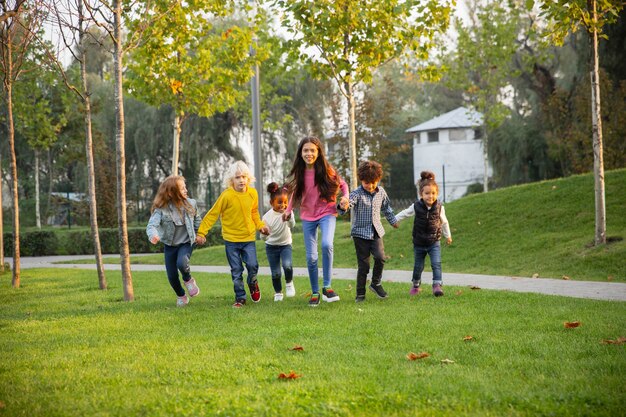 Ciepły. Międzyrasowa grupa dzieci, dziewcząt i chłopców bawiących się razem w parku w letni dzień.