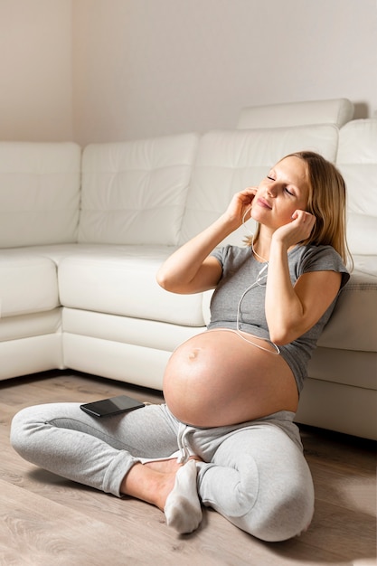 Bezpłatne zdjęcie ciężarna blondynki kobieta słucha muzykę