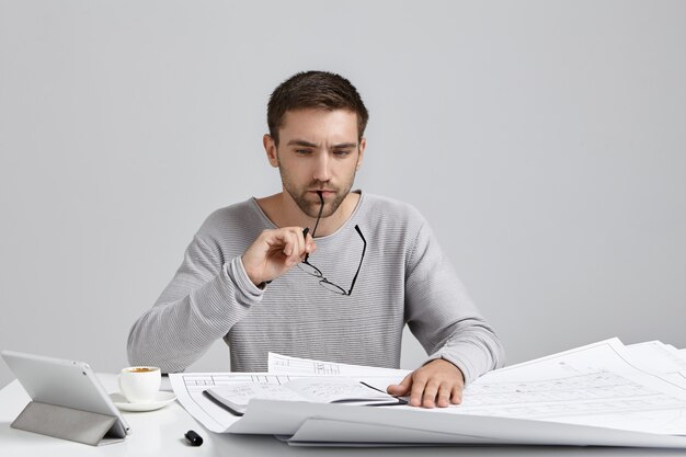 Ciężko pracujący projektant zdejmuje okulary, ma przemyślany wyraz twarzy