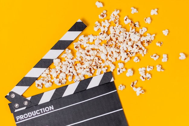 Bezpłatne zdjęcie clapperboard filmu z popcorns na żółtym tle