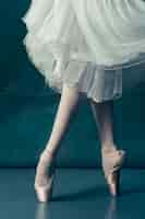 Bezpłatne zdjęcie close-up baleriny nogi w pointes na szarej drewnianej podłodze