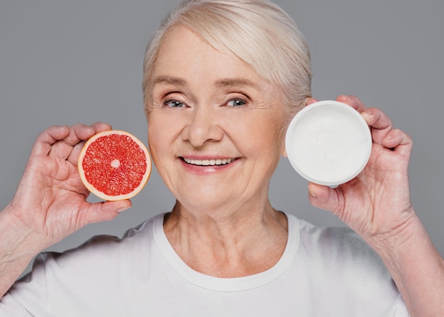 Close-up kobieta trzyma czerwoną pomarańczę i śmietankę
