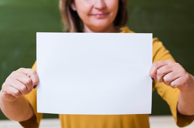 Close-up nauczyciel trzymając pusty arkusz papieru