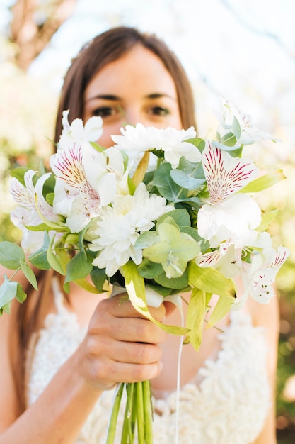 Close-up z oblubienicy gospodarstwa bukiet białych kwiatów przed jej twarz
