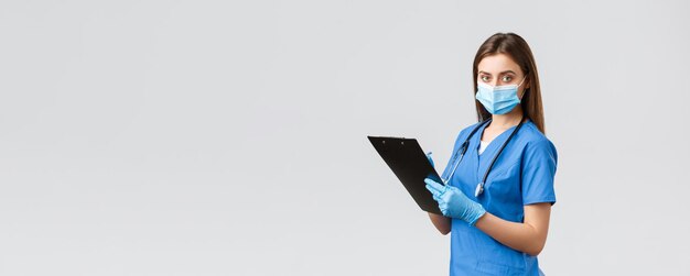 Covid19 zapobieganie wirusom zdrowie pracownicy służby zdrowia i koncepcja kwarantanny Profesjonalna pielęgniarka lub lekarz w niebieskiej masce medycznej i rękawiczkach spisujących informacje o pacjencie za pomocą schowka