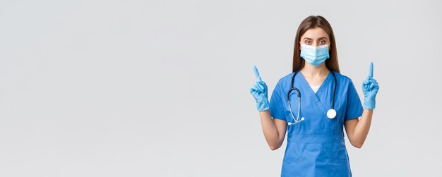 Covid19 zapobieganie wirusowi zdrowie pracowników opieki zdrowotnej koncepcja Poważna i pewna siebie pielęgniarka w niebieskiej masce medycznej ŚOI wskazujące palce w górę informują pacjentów, jak zapobiegać infekcji koronowej