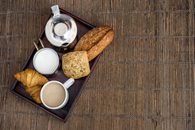Croissant, ciastko, chleb z herbatą i mlekiem podczas śniadania