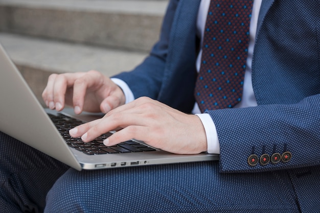 Crop biznesmen pisania na klawiaturze laptopa