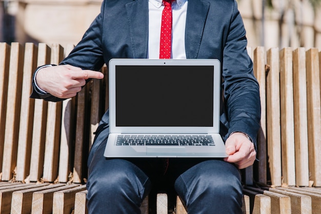 Bezpłatne zdjęcie crop biznesmen wskazuje przy laptopem