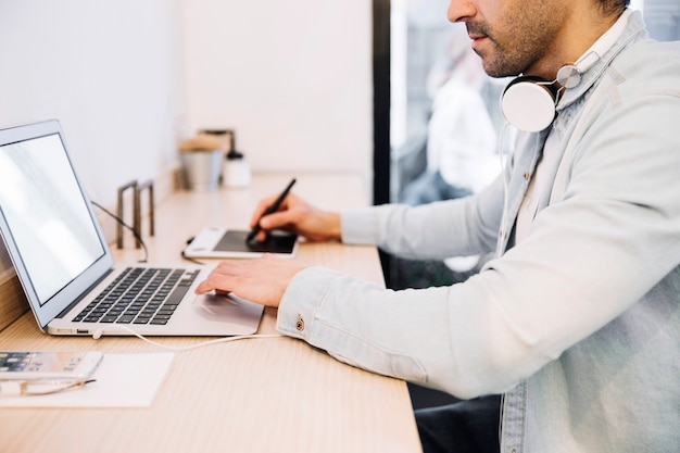 Crop męski używa laptop i rysunkowa pastylka