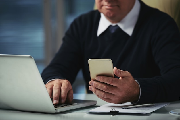 Cropped mężczyzna sprawdza wiadomości na jego telefonie w biurze