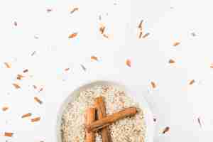 Bezpłatne zdjęcie cynamonowi kije nad uncooked ryżowym pucharem przeciw białemu tłu