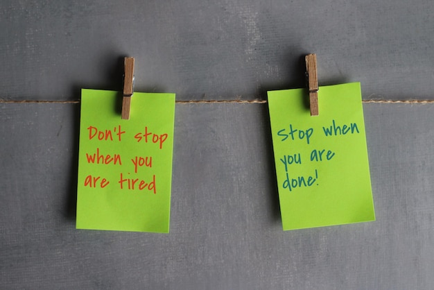 Cytaty motywacyjne „nie przestawaj, gdy jesteś zmęczony, przestań, gdy skończysz!” na papierach wiszących na linie przed betonową ścianą.