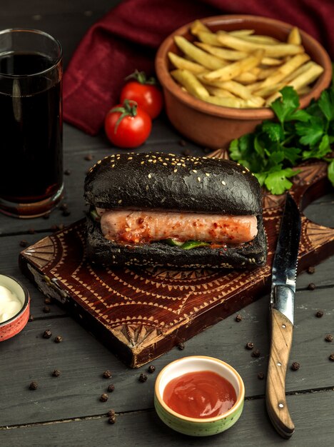 Czarna kanapka z kiełbasą i ogórkiem podana z frytkami