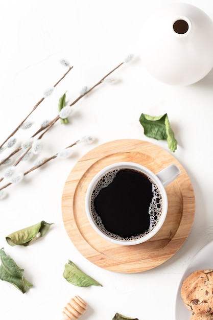 Czarna kawa w filiżance i liście na białym stole