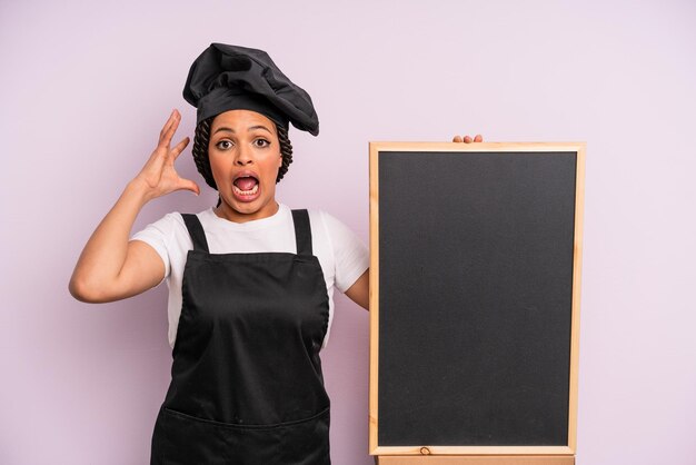 Czarna kobieta afro krzyczy z rękami w powietrzu. koncepcja szefa kuchni i tablicy