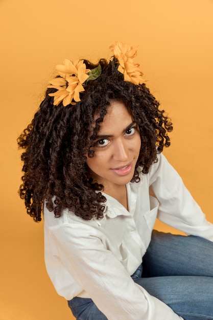Czarna kobieta siedzi z kwiatami we włosach