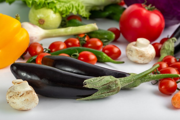 Czarne bakłażany świeże i dojrzałe kolorowe warzywa, takie jak czarne bakłażany i inne na białym biurku