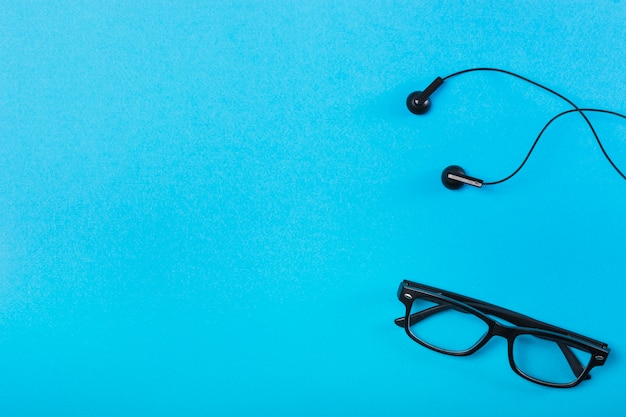 Czarni eyeglasses i słuchawka na błękitnym tle