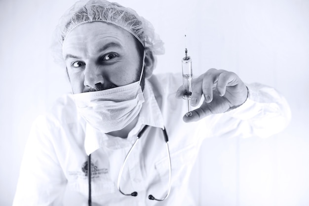 Czarno-białe zdjęcie brodatego lekarza w białym fartuchu i starej strzykawce
