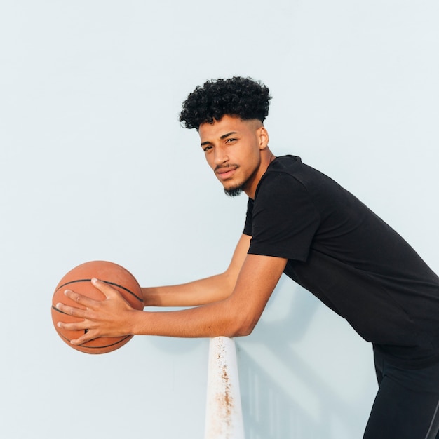 Bezpłatne zdjęcie czarny sportowiec z koszykówką opierając się na poręczy