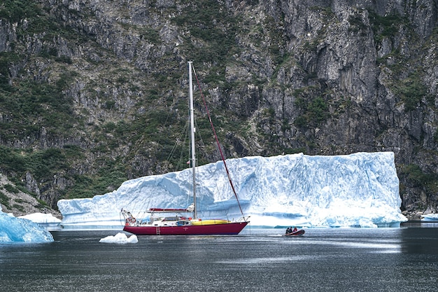 Czerwona łódź na wodzie obok lodowej góry