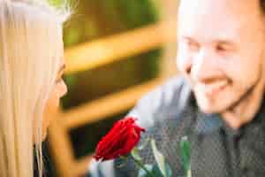 Bezpłatne zdjęcie czerwona róża między twarzą pary