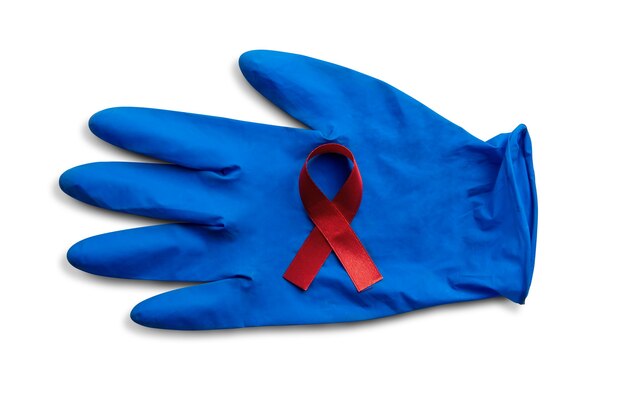 Czerwona wstążka i rękawiczki medyczne z białym tłem. Świadomość wstążki HIV Aids