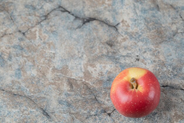 Czerwone jabłko na białym tle na teksturowanej powierzchni