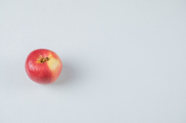 Czerwone jabłko na białym tle na teksturowanej powierzchni