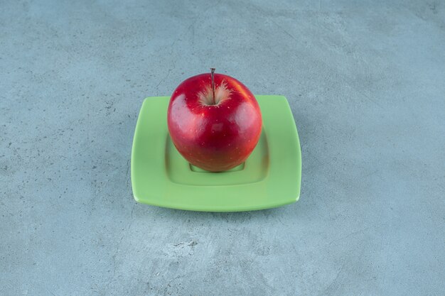 Czerwone jabłko na talerzu, na marmurowym tle. Zdjęcie wysokiej jakości