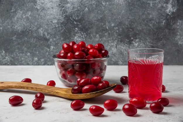 Czerwone jagody derenia w szklanej filiżance z sokiem na bok.