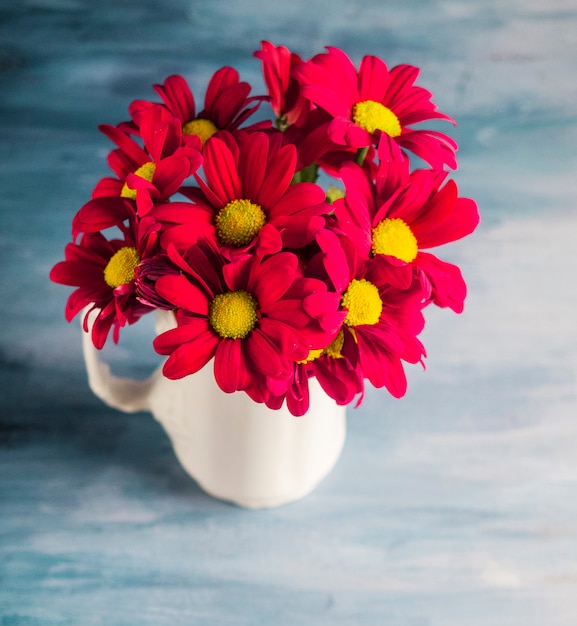 Czerwone kwiaty w wazonie na szarym stole