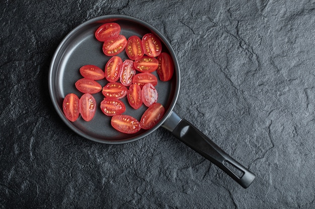 Czerwone pomidory koktajlowe pokrojone na pół na patelnię.