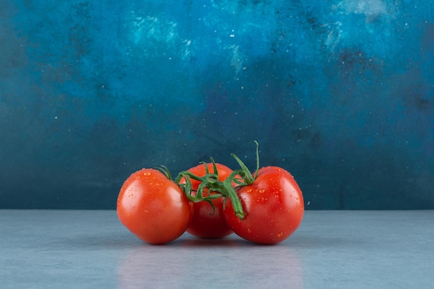 Czerwone pomidory z kroplami wody na niebiesko.