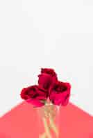Bezpłatne zdjęcie czerwone róże w szklanej wazie na światło stole