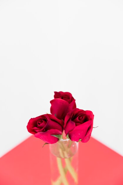 Czerwone róże w szklanej wazie na światło stole
