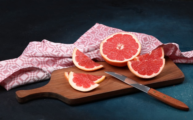 Czerwoni świezi Grapefruitowi Plasterki Na Drewnianej Desce Z Nożem.