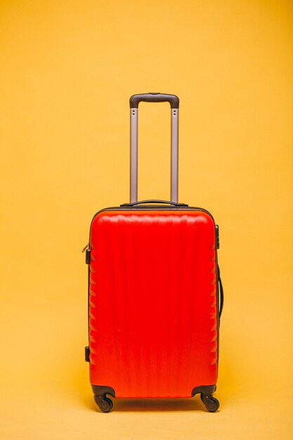 Czerwony bagaż na żółtym tle odizolowywającym