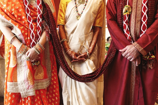 Bezpłatne zdjęcie czerwony szal łączy rodziców panny młodej ubranych na indyjskie wesele