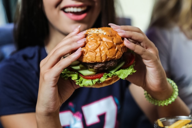 Człowiek będzie jeść mięso burger sałata ogórek pomidor widok z boku