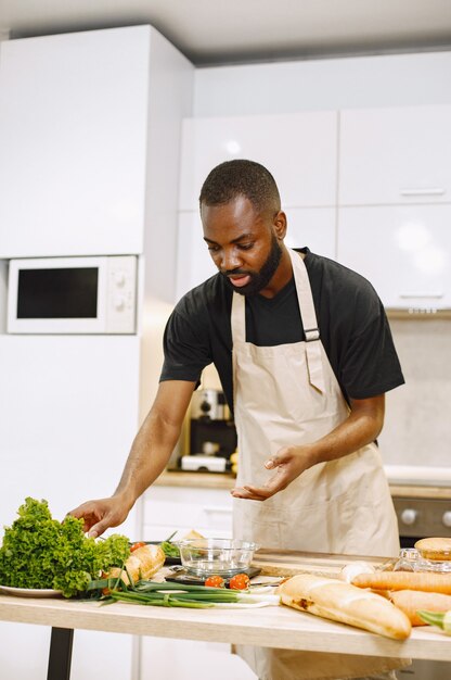 Człowiek gotowanie. Afro-człowiek przebywający w kuchni. Mężczyzna w czarnej koszulce.