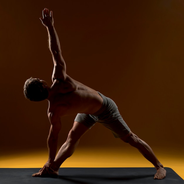 Bezpłatne zdjęcie człowiek na matę do jogi robi ćwiczenia