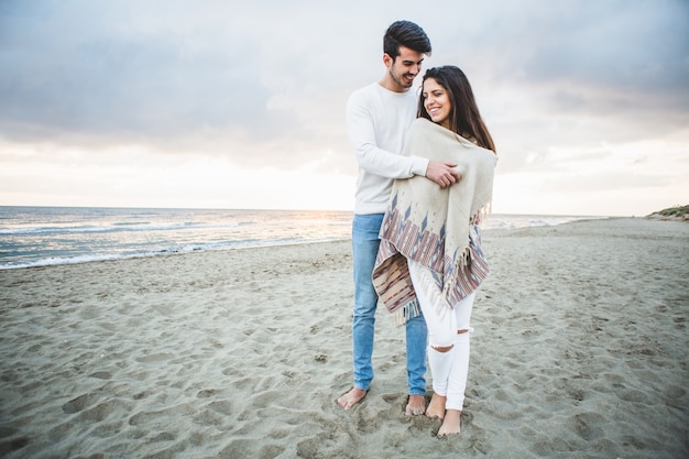Bezpłatne zdjęcie człowiek obejmując swoją dziewczynę na plaży