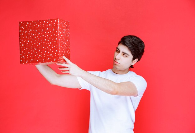 Człowiek posiadający czerwone pudełko i sprawdzanie go